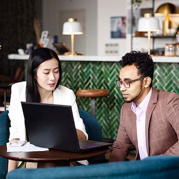 man and woman looking at a laptop at a table at a restaurant